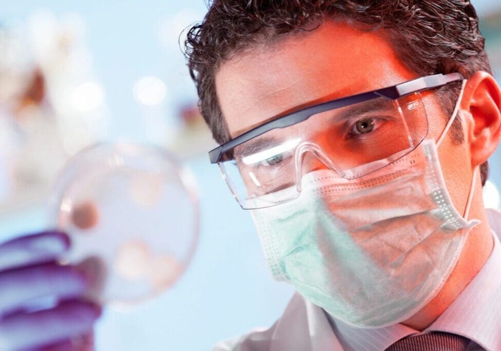 A man in a lab coat holding a petri dish.